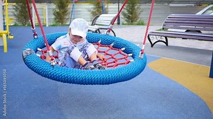 Child playing on the Playground, swinging on the swings . Active outdoor sports
