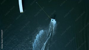 OVERHEAD aerial drone shot of female wake boarding in a cable wakepark on a lake. 4K UHD 60 FPS