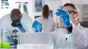 Portrait smiling young researcher working in the lab with chemicals and test tubes.