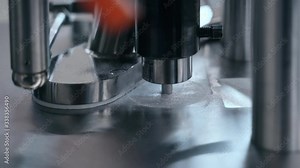 Closeup view of manufacturing process of pills during working day at pharmaceutical factory spbas. Metal equipment moves and produces white medical drugs s in workshop of modern plant. Concept