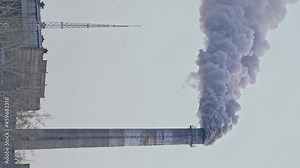This smoke coming from the chimney in a factory. Harmful emissions into the atmosphere, from the pipe. Serious damage the environment. Plant stack Coaling station. Vertical video. Dark sad view.