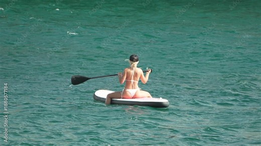 Woman paddleboard ocean, female paddling calmly on stand-up board in turquoise water, summer vacation activity