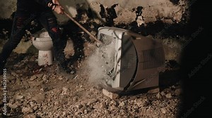 The guy smashes the screen of an old TV with a sledgehammer. Fragments from the screen fly apart. Slow motion shots