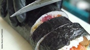 Art of sushi-making as the skilled hands of a professional chef expertly construct a sushi roll from nori, rice, tuna, shrimp, and salmon, elevating the culinary experience with precision and expertis