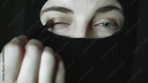 Muslim makeup step by step tutorial. A girl with beautiful eyes in a hijab does makeup. Close-up portrait of a charming Muslim woman in make-up.