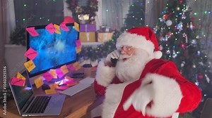 Santa actively gestures on the phone while multitasking on his computer, fully immersed in the busy Christmas preparations.