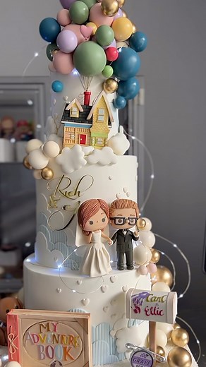 Jackie Florendo 🇵🇭🇩🇪 on Instagram: "Proudly wear your grapesoda pin and soar on a whimsical and imaginative adventure with Pixar’s Up Wedding cake. The cute little details bring to life scenes from the animated movie like the house (even the mailbox), lovable Dug, their cherished adventure book scrapbook and ofcourse Carl and Ellie on their wedding day. Your traditional white cake takes flight into a world of playful awe and wonder! #cbjfweddings #cbjfdisneypixar #cbjfpixar #cbjfmoviestocake