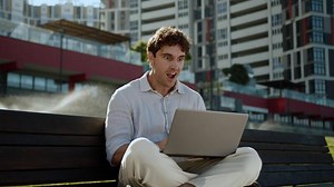 Happy shocked Caucasian man using laptop computer excited good news win enjoy male working success guy businessman employee achieve business city outside office chatting online victory amazing wonder