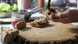 Hands preparing sandwich. Duck pate and caramelized onions.