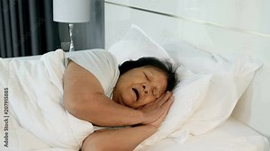 4k of old woman sleeping and snore on a bed in bedroom
