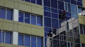 Window cleaners. Qualified high-rise workers wash the glass windows of an office building.