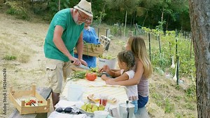 Multi-generational family preparing vegetable salad outside and composting vegetable scraps