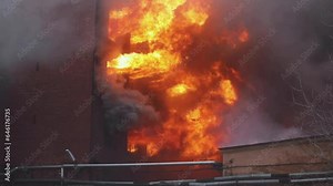 Massive large blaze fire in the city, brick factory building on fire, hell major fire explosion flame blast, with firefighters team firemen on duty, arson, burning house damage destruction