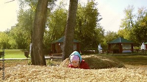 Cute smiling little girl jumping from one haystack to another