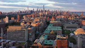 Aerial view over the Morningside Heights neighborhood of Manhattan, NYC at golden hour sunrise. Epic view of midtown skyline straight ahead with gorgeous array of colors. in 4K.