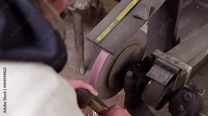 craftsman whet an axe at an old whetstone in a grindery