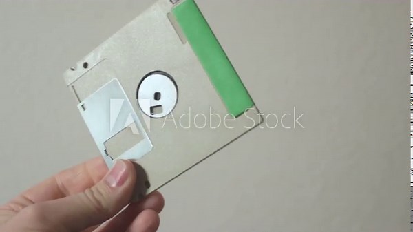 A 3.5 inch floppy disk held up and flipped over. With a handwritten label describing the contents in pencil.