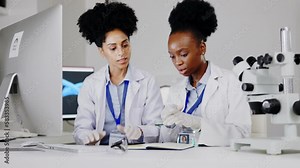 Scientist, teamwork and women with computer writing research results and information. Science, collaboration and female medical doctor with lab assistant write in notebook for petri dish experiment.