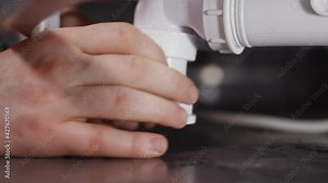 Plumber installing bath trap. Close-up view.