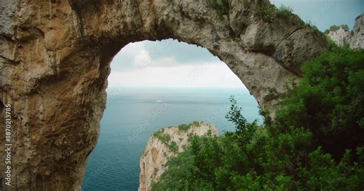 Arco Naturale stone arch frames the sea and cliffs on summer day in Capri Italy