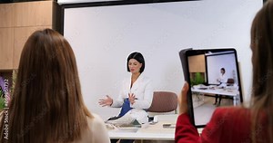 Interior design blogger in white blazer records online course. Confidently presenting design concepts, using digital tools. modern online education, creativity, professionalism, and engagement.