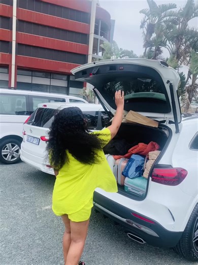 Woman Organizing Trunk of White SUV in Bright Outfit