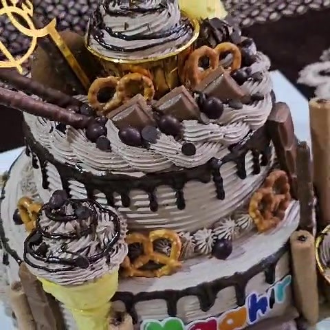 "Chocolate cake loaded with chocochips" For any customized cake Contact on 0111693235 This is a decadent, two-tiered chocolate birthday cake topped with whipped chocolate frosting, a rich chocolate drip, and an assortment of candies, pretzels, chocolate bars, wafer sticks, and ice cream cone decorations. | Cake Bake Take Nairobi