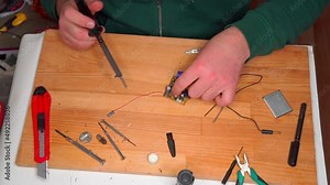 Closeup view of simple electric circuit, breadboard with electrical components, diode, resistors, soldering electrical colored cables and wires. Hand soldering station. Electronic parts