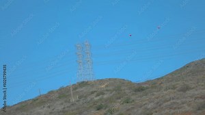 View of utility poles on a hill against a clear blue sky in California in slow motion 120fps