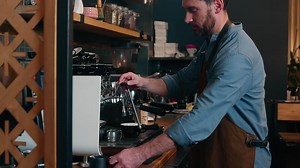 Caucasian waiter staff man guy employee making drink latte in cafe worker adding milk foam in cappuccino cafeteria barista using coffee machine catering small business male in apron serving customer