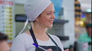 Happy waitress taking food orders and interacting with customers standing inside restaurant