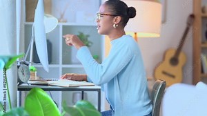 Focused remote student typing and doing research for an academic essay or article while writing notes at a computer desk inside. Female university learner studying for a test or college assignment