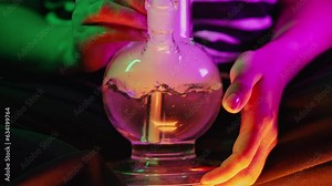 Woman smoking indica marijuana, water bong in neon light at home. Cannabis.