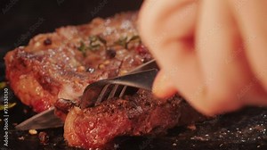 Fresh marbled beef with pepper, salt and rosemary close-up macro. Cutting with knife juicy steak on plate. Premium organic wagyu meat