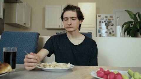clip-4002221741-man-sitting-kitchen-eating-dumplings-thoughtful-expression