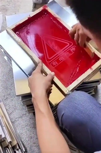 Stamping a triangular logo onto a metal storage box using a wooden screen coated with printing paste