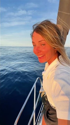 Pod of Wild Dolphins Swim with Sailboat in Ocean