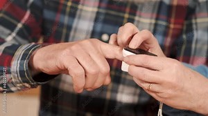 Self-isolation during covid-19 pandemic. The senior couple is staying at home to prevent getting virus. The elderly husband is monitoring blood oxygen concentration with polse oxymeter.