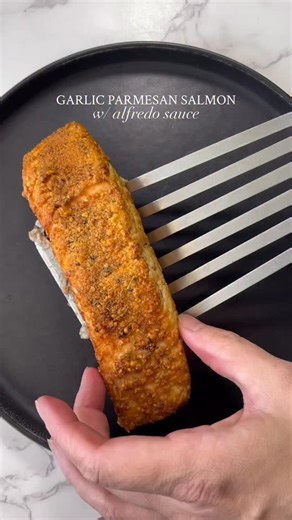 One of my go to easy dinners 😍 This is my Garlic Parmesan Salmon w/ Creamy Alfredo Sauce and it is so soooooo good😉 y’all gotta try it. I hope you enjoy! Save this to make later • follow for more of my easy recipes every week! For the salmon: 1 Salmon filet Heavy pinch of Garlic powder Paprika, salt, black pepper, oregano 1-2 tbsp Parmesan *Oil Sauce: 2-3 tbsp Alfredo sauce Toppings: Basil TJ’s Chili Onion Crunch - Add salmon filet to a bowl. -Coat with a little oil. -Add seasonings and Parmes