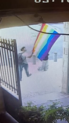 Viral News 🔥 on Instagram: "⚠️ Unusual moment captured on security cameras — context unclear Security footage shows two people walking out of what appears to be a courtyard when one of them briefly stops and looks up at a nearby flag. After a short pause, he reaches toward it and removes it before continuing to walk, while the other person stays still. A short time later, another individual can be seen entering the frame. Since only a clip is available, it’s unclear why this happened, what was 