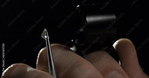 Gemologist checks diamond quality under magnifying glass. Diamond or gem grading and valuation. Close-up side view