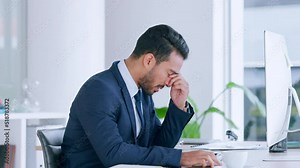 Angry businessman annoyed with his broken computer, getting frustrated while sitting in a modern office. Annoyed male looking upset with slow internet and bad connection while browsing