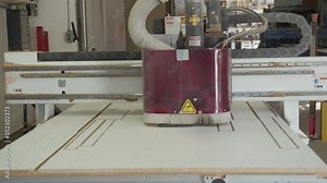 CNC router cutting design in material without people. Robotic wood cutting tool uses programming to make precision cuts in wood laminate board. Manufacturing process in fabrication shop.