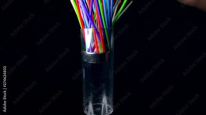 This video shows a hand opening and closing a straw dispenser with colorful straws on a black background.