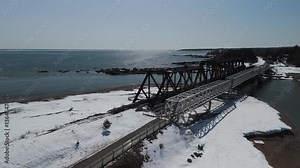 Winter Tranquility: 60fps Drone Flyover of a Snow-Covered Train Bridge in Chandler, Québec, Gaspésie