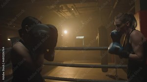 Medium shot of female instructor using punch mitts while strong woman jabbing at boxing ring