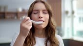 Closeup young woman standing with soup spoon at home kitchen....