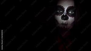 Woman with makeup for the day of the dead smiles enigmatically in spotlight. Theme of costumes and transformation for holiday of Halloween. Traditional skull makeup for the day of the dead celebration
