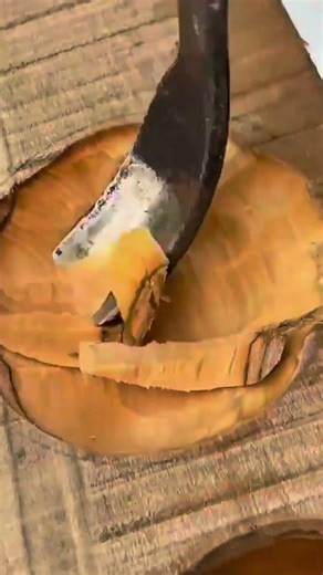 hollowing out a wooden bowl using a curved adze or specialized gouge to create a smooth