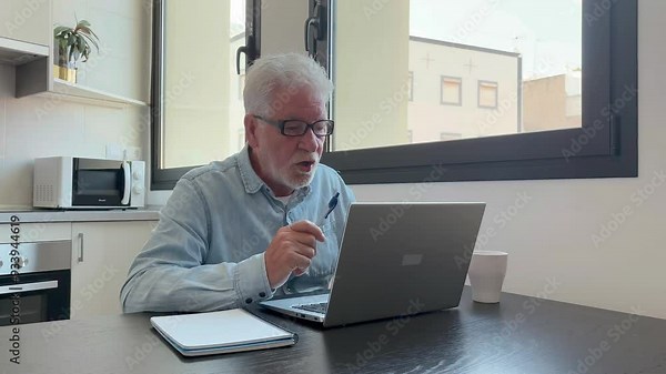 Angry senior businessman arguing animatedly connected in video conference via laptop pc. Handsome bearded mature man arguing annoyed with his interlocutor